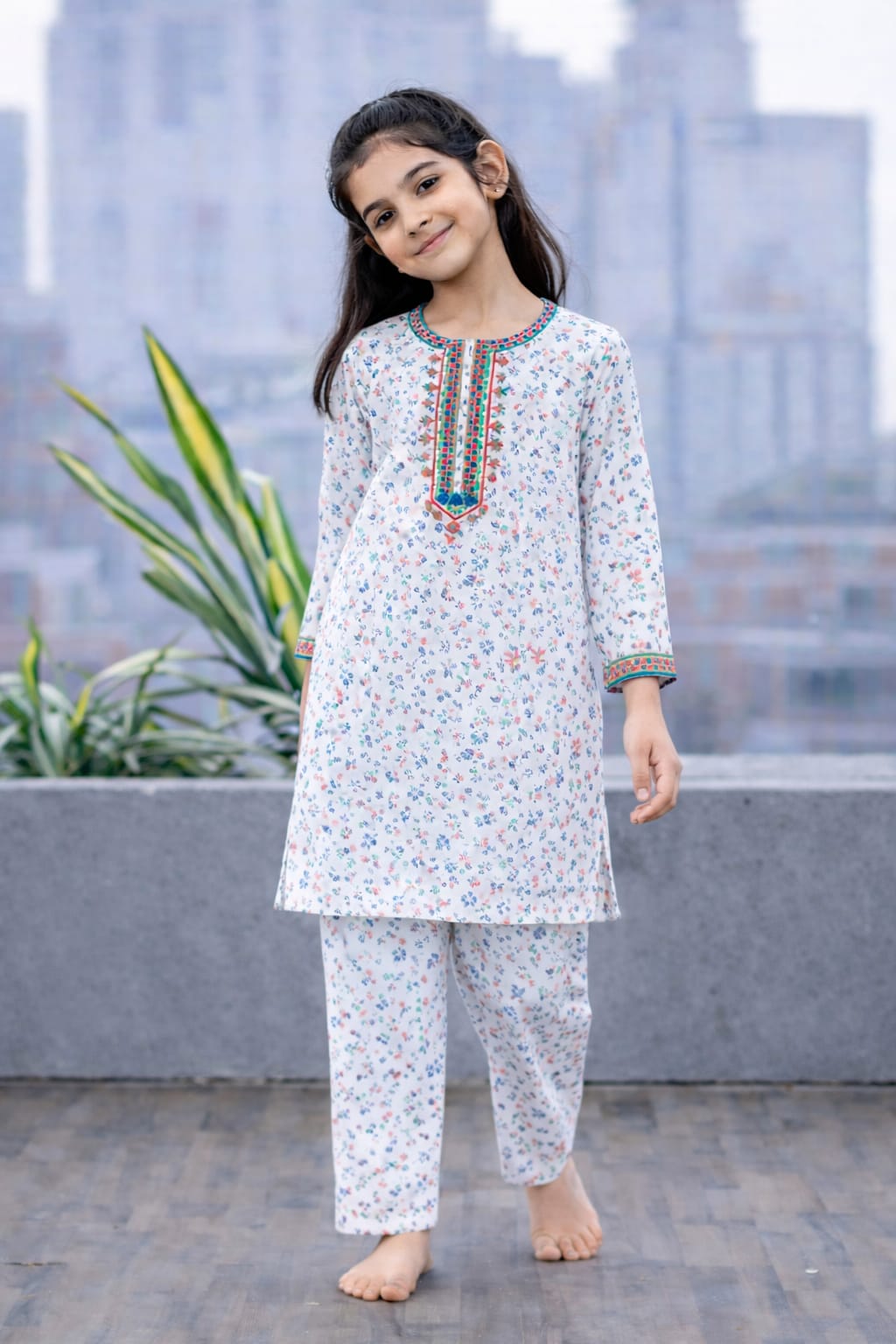 White floral printed cotton 2-piece outfit for girls with multicolor embroidered neckline kurti and straight pants, balcony setting Pakistan

