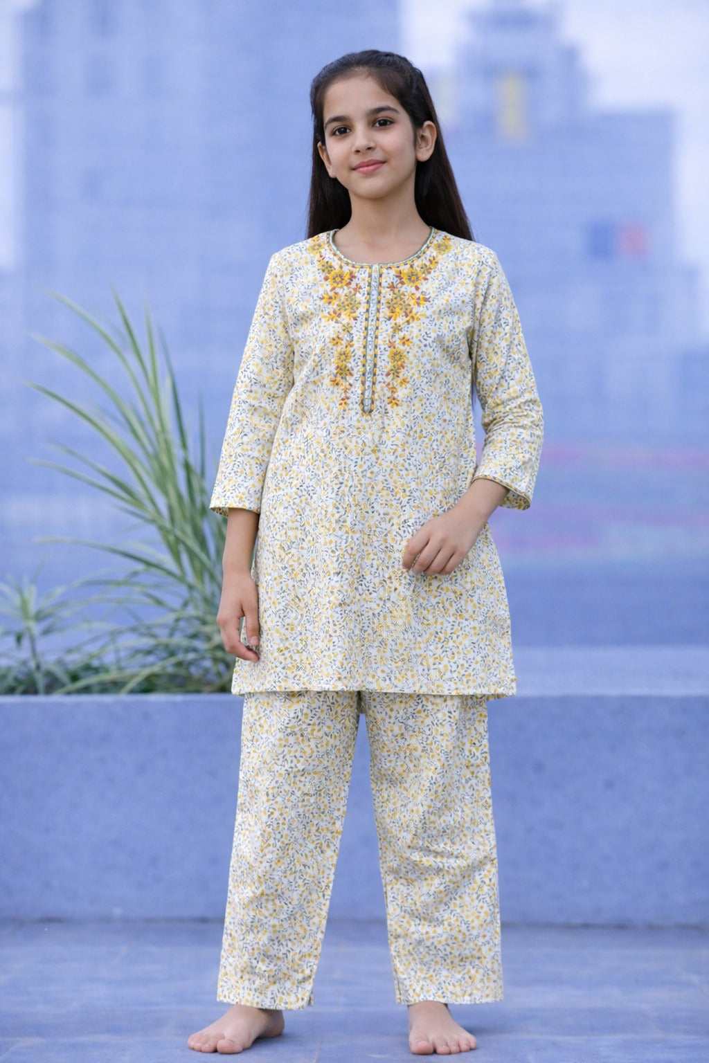 Light yellow floral cotton 2-piece outfit for girls with embroidered neckline kurti and straight pants, balcony setting Pakistan
