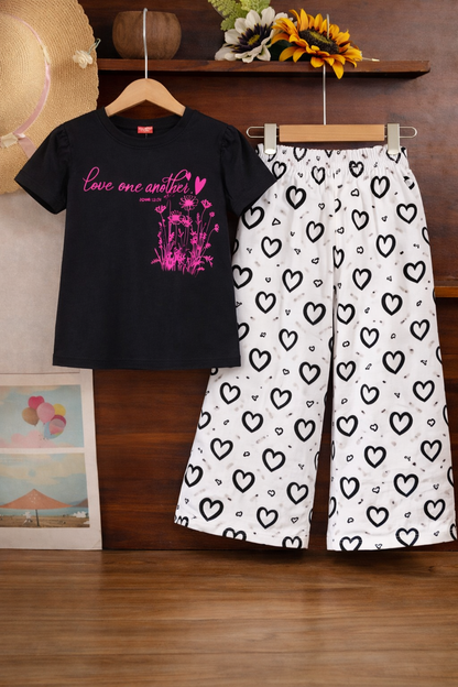 Black graphic cotton t-shirt with white heart print pants girls outfit on hanger.